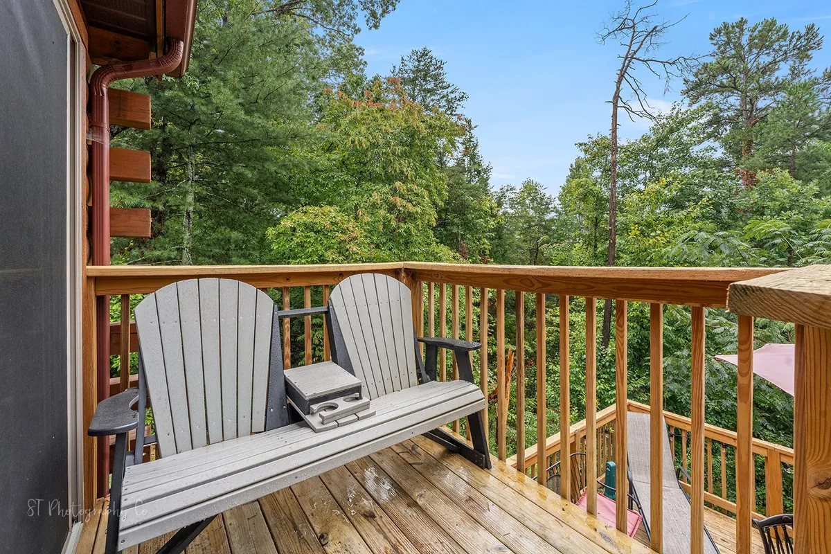 This tranquil image features a wooden deck with classic Adirondack chairs overlooking the forest, set up to invite quiet contemplation or social moments. The natural landscape and surrounding trees evoke peaceful mornings with coffee or starlit nights in the fresh mountain air.