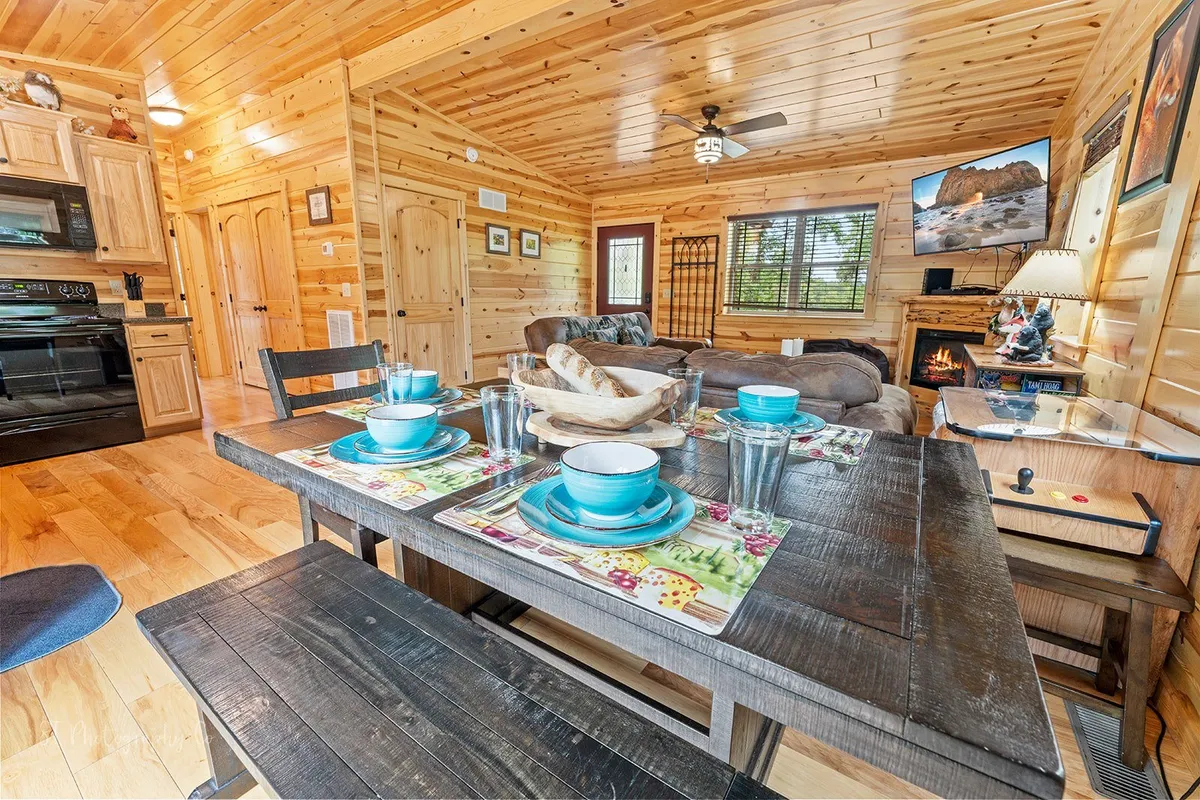 A spacious common area with a dining table set for a meal, comfortable seating, a cozy fireplace, and visible kitchen appliances. The scene invites guests to gather, relax, and plan outings, highlighting both value and convenience.