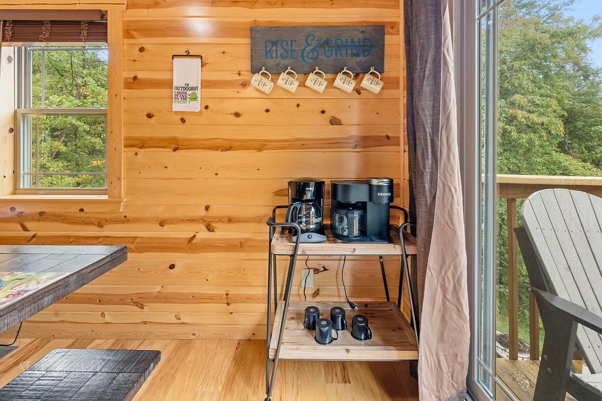 A charming coffee station set against wooden paneling, with a window offering a view outside and a decorative sign adding a personalized touch. The cozy setting suggests easy mornings before a busy day of exploration.